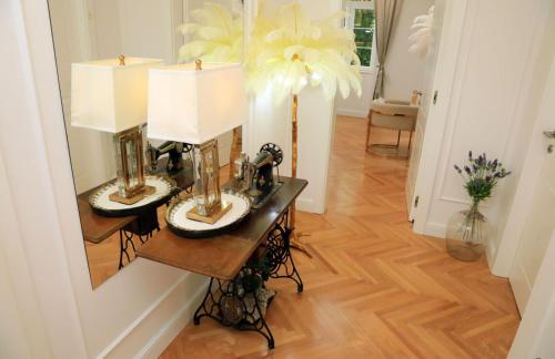 a hallway with a table with two lamps and a mirror at Garden Luxury Rooms in Split