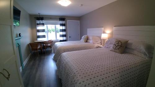 a bedroom with two beds and a table and a window at North Rustico Harbour Inn in North Rustico