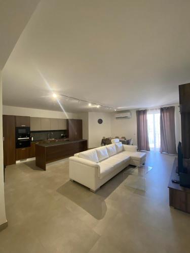 a living room with a white couch and a television at An immaculate 3 bedroom apartment in Gudja in Gudja