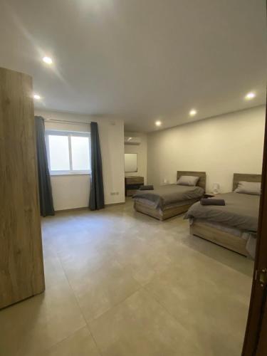 a large room with two beds and a window at An immaculate 3 bedroom apartment in Gudja in Gudja