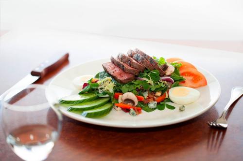 a plate of food with meat and vegetables on a table at Vancouver Airport Marriott Hotel in Richmond