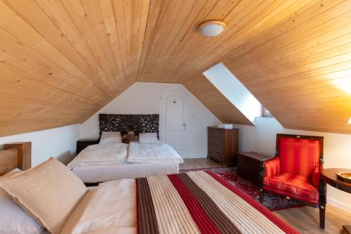 a attic bedroom with a bed and a chair at Natura vendégház in Abaújvár