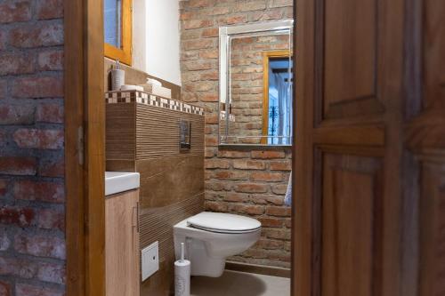 a bathroom with a white toilet and a brick wall at Natura vendégház in Abaújvár