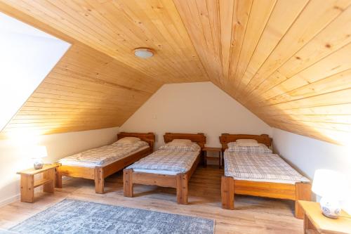 a room with three beds and wooden ceilings at Natura vendégház in Abaújvár