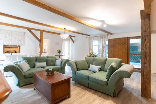 a living room with two green couches and a table at Natura vendégház in Abaújvár