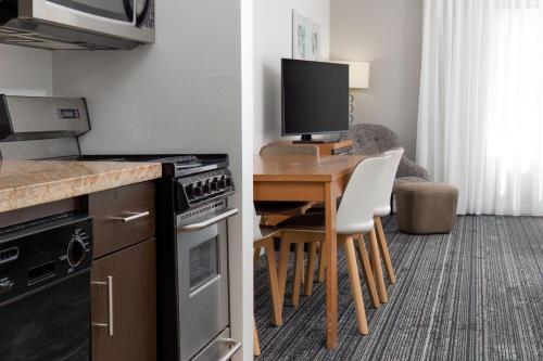 a kitchen with a table with chairs and a television at TownePlace Suites by Marriott Erie in Erie