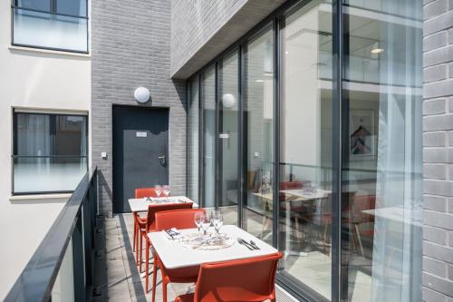 a balcony with red chairs and tables and glass windows at Oh Activ Cergy in Cergy