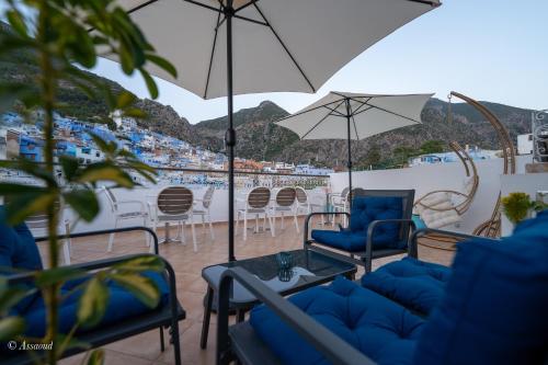 a patio with chairs and tables and an umbrella at Dar Kisania in Chefchaouene