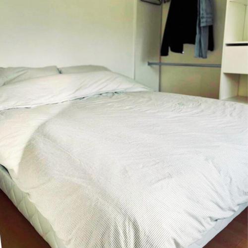 - un lit blanc dans une chambre avec placard dans l'établissement COSY Apartment near the Center of Paris, Porte de Clichy, à Clichy