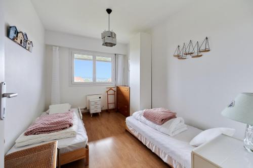 deux lits dans une chambre aux murs blancs et au parquet dans l'établissement Le Plein Soleil - Appt pour 6 proche de la plage, à Villers-sur-Mer