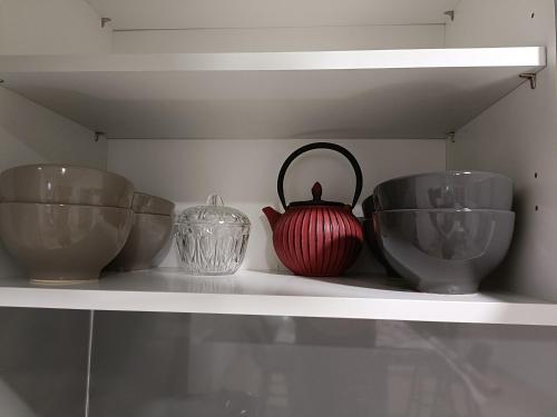 a shelf with three bowls and a red vase on it at L'étoile de Zakiel in Cambayrac