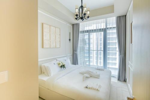 a white bedroom with a large white bed and a window at Cozy 1 BR apartment in Dubai near Burj khalifa in Dubai