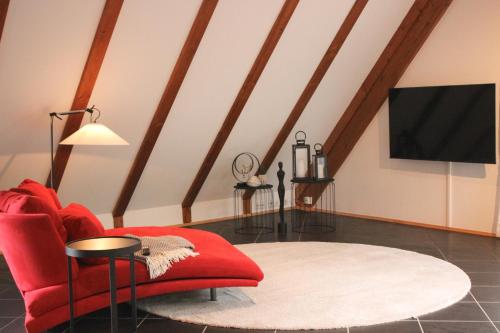 a living room with a red chair and a flat screen tv at Gasthof zum Grünen Baum Komfort Suite in Rothenburg ob der Tauber