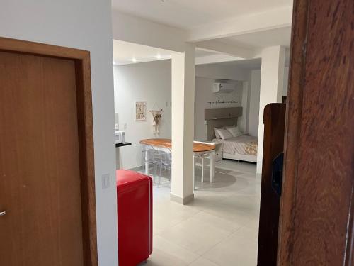 a living room with a red suitcase and a table at Studios Aromas do Campeche - Floripa in Florianópolis