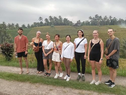 a group of people standing in front of a field at Red Roses Guest House By Balitrees in Selemadeg