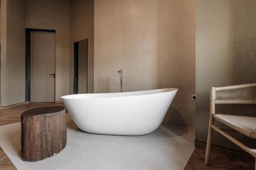 a large white tub in a bathroom with a wooden stump at Castel Mimi Wine Resort in Bulboaca