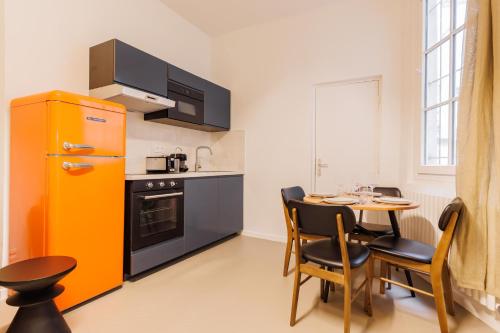 Il comprend une cuisine équipée d'une table et d'un réfrigérateur jaune. dans l'établissement Cosy apartment - 1BR-4P - Marais-Place des Vosges, à Paris