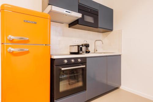 Il comprend une cuisine équipée d'un réfrigérateur orange. dans l'établissement Cosy apartment - 1BR-4P - Marais-Place des Vosges, à Paris