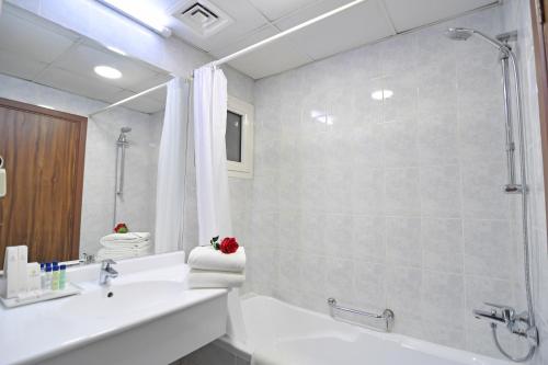 a white bathroom with a shower and a sink at Nejoum Al Emarat in Sharjah