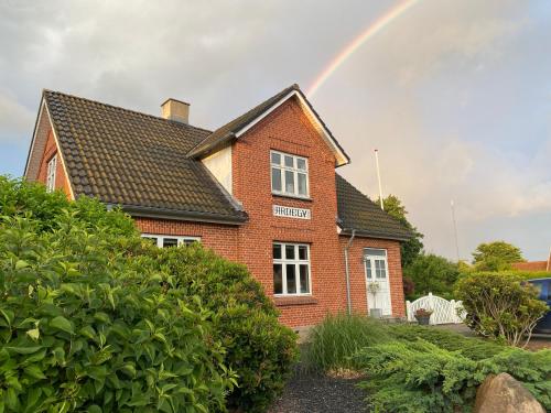 a rainbow in the sky above a brick house at Wonderful house & garden in Tommerup