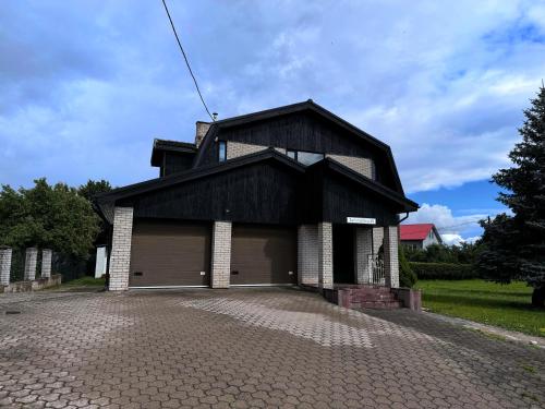 a black house with a garage on a driveway at Tammetõru Villa in Tartu