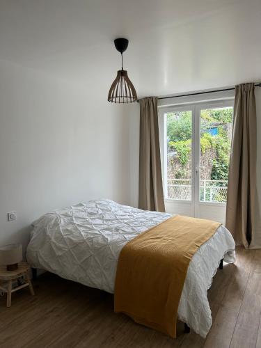 une chambre avec un lit et une grande fenêtre dans l'établissement Appartement bocage virois, à Vire