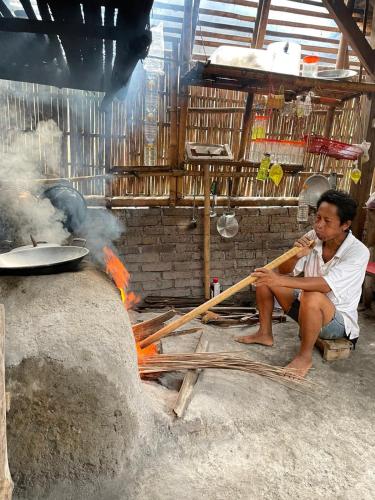 a man sitting on the ground next to a fire at Red Roses Guest House By Balitrees in Selemadeg