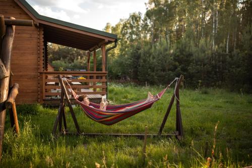 a man sleeping in a hammock in a field at Głuszecki las in Skórcz