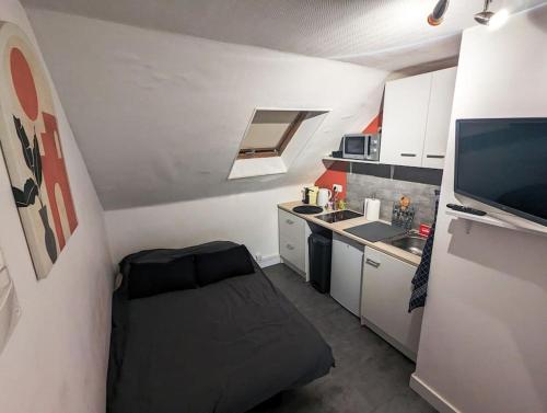 Cette chambre comprend une petite cuisine avec une chaise noire. dans l'établissement Studio calme - Proche Zénith, à Caen