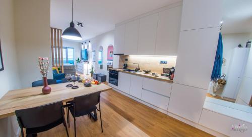 a kitchen with white cabinets and a wooden table at Iris Studio Apartment in Mostar