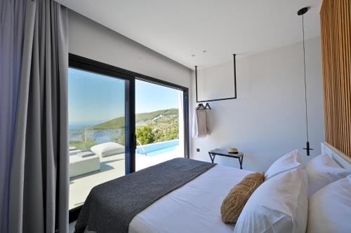 a bedroom with a bed and a view of the ocean at Etherial View Villas Skiathos in Skiathos