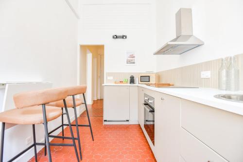 une cuisine blanche avec un comptoir et un tabouret dans l'établissement Appart 2 ch - proche métro Périer et Vélodrome, à Marseille