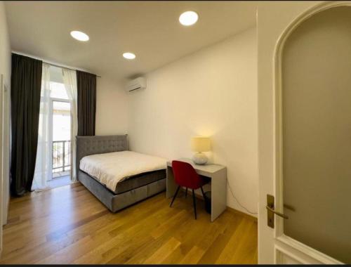 a bedroom with a bed and a desk with a red chair at City center appartment in Pula