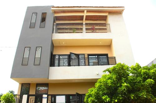 a white building with black balconies and a tree at MB Properties - Brufut Garden Apartments in Brufut