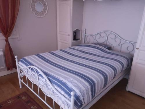 - un lit blanc avec une couverture rayée bleue et blanche dans l'établissement La Porte Bleue, à Vouneuil-sous-Biard