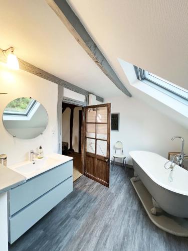 une salle de bain avec une baignoire, un lavabo et un miroir dans l'établissement Pierres de Loire, à Saint-Benoît-sur-Loire