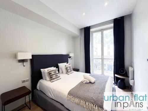 une chambre avec un lit avec une grande fenêtre dans l'établissement Urban Flat 60 - Sublime Parisian Flat in Paris, à Paris
