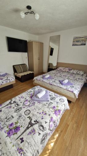 two beds in a room with purple and white blankets at Apartmani Proleće in Jošanička Banja