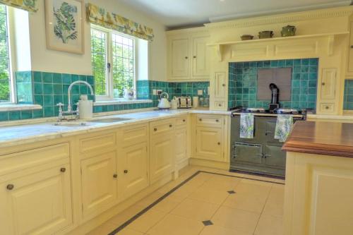 a kitchen with white cabinets and a sink and a stove at Cotswold Country house Villa Retreat With Pool in Rowde