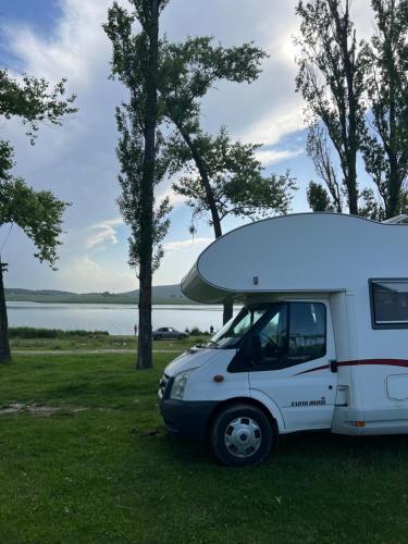 a white van parked in the grass next to a lake at Camper Mobile Motorhome in Tbilisi City