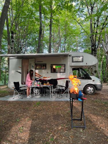 a woman sitting at a table in front of a caravan at Camper Mobile Motorhome in Tbilisi City