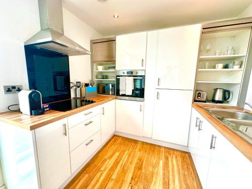 a kitchen with white cabinets and a wooden floor at Media City Salford Quays in Manchester