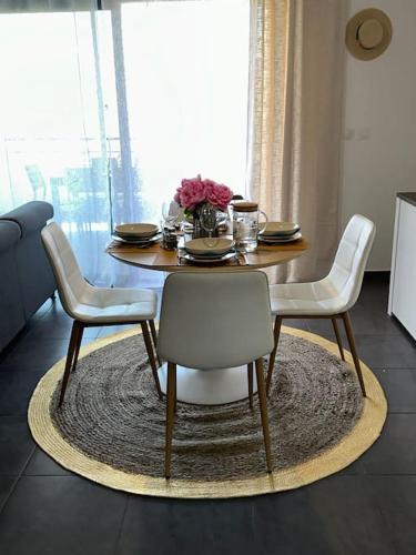 a dining room table with white chairs and a table and a table at 5 min des plages - Appt 2 chambres A Casa Bella in Lucciana