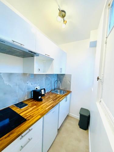une cuisine avec des armoires blanches et un comptoir en bois dans l'établissement Studio - Au calme quartier Pleyel RER Ligne 14, à Saint-Denis