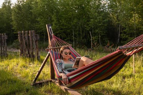 a woman sitting in a hammock with a laptop at Głuszecki las in Skórcz