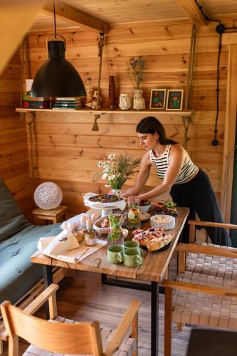 a woman preparing food on a table in a cabin at Głuszecki las in Skórcz