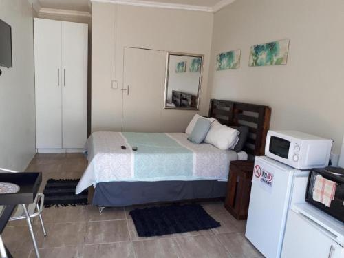a bedroom with a bed with a microwave and a refrigerator at 8 Soenie Avenue Self-Catering in Pretoria