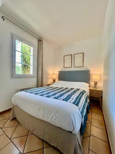 une chambre avec un grand lit et une fenêtre dans l'établissement Grimaud La Palmeraie, à Grimaud