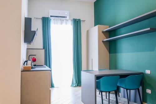 a kitchen with a table and two blue chairs at Rooftop Parthenopeo Contemporary Rooms in Naples