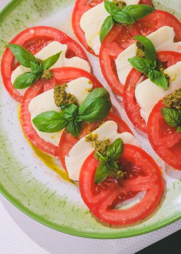 a plate of food with tomatoes and basil on it at Vila Perast Boutique Hotel in Perast